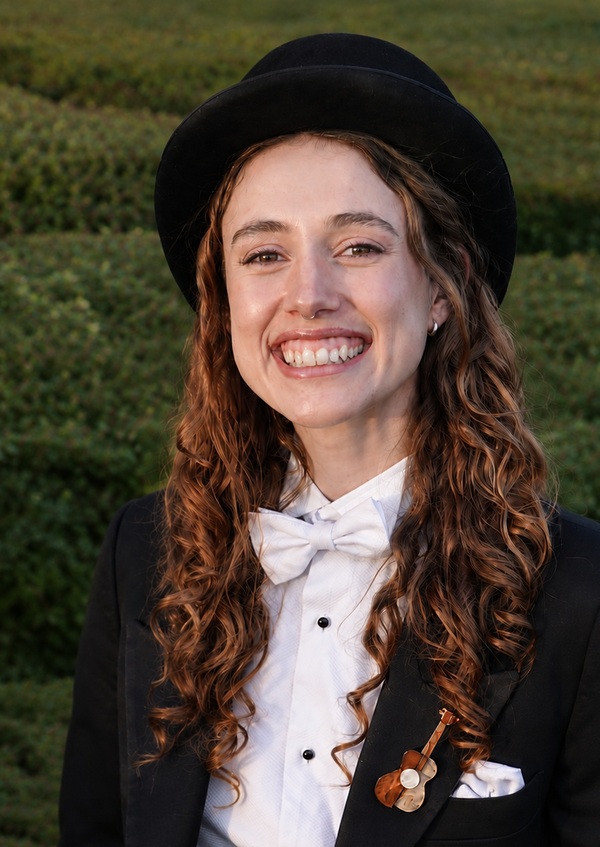 Minna Squire in a top hat and tuxedo, smiling