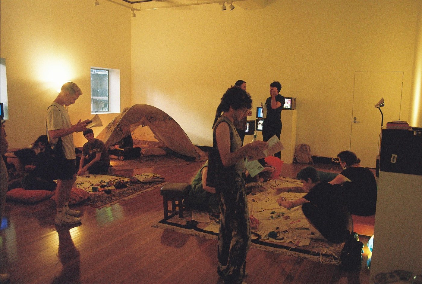 The Utopography exhibition room: tent, screens and visitors working on maps