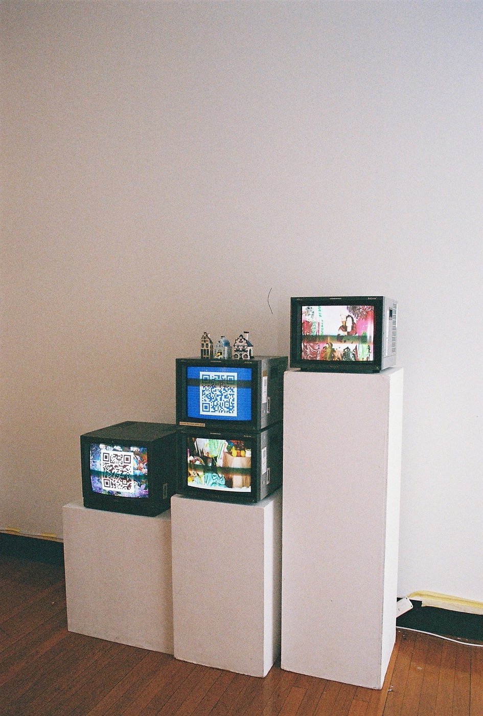 Stacked CRT monitors showing QR codes and video works